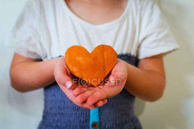 Cropped image of Girl holding heart shaped pumpkin — Stock Photo