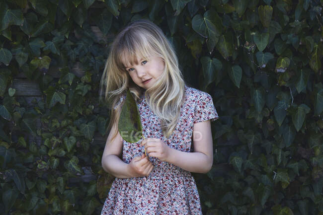 Retrato de una niña sosteniendo una hoja - foto de stock
