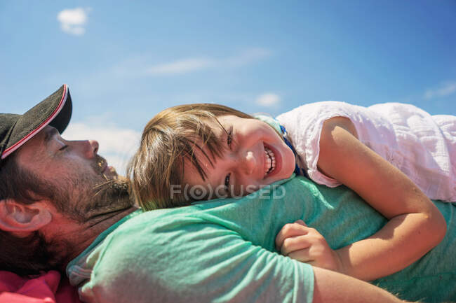 Chica sonriente acostada en el pecho de su padre - foto de stock
