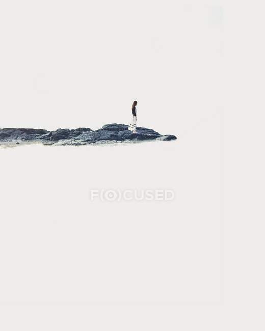 Mulher de pé sobre rochas à beira-mar — Fotografia de Stock