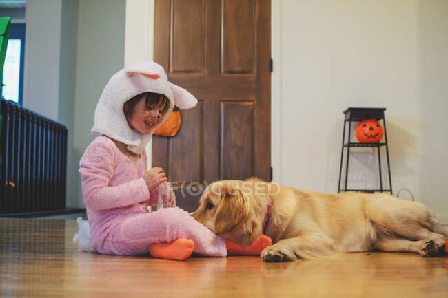 Ragazza in costume da coniglio giocare con Golden Retriever cane — Foto stock