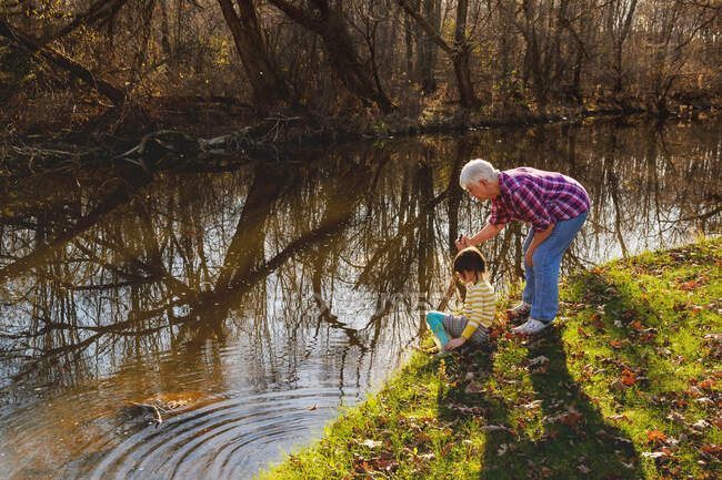 Бабуся стоїть біля річки зі своєю онукою — стокове фото