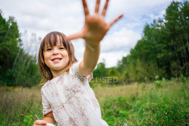 Retrato de una niña sosteniendo su mano en el aire - foto de stock