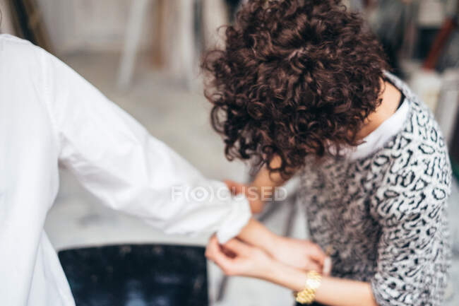 Woman turning up a woman's shirt sleeve — Stock Photo