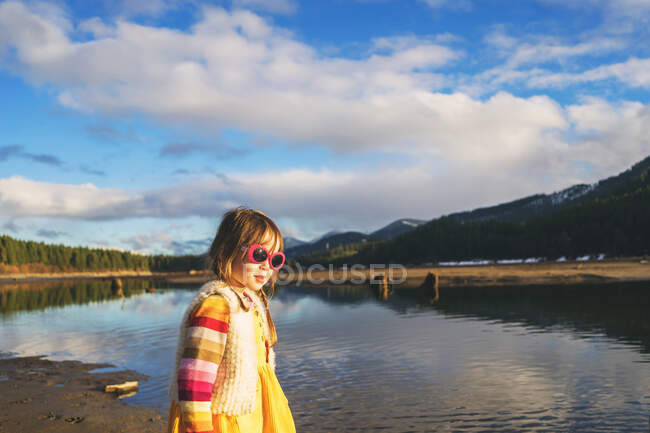 Girl wearing sunglasses standing by a lake — Stock Photo