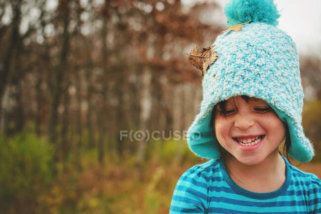 Portrait of a smiling girl with autumn leaf on her hat — Stock Photo