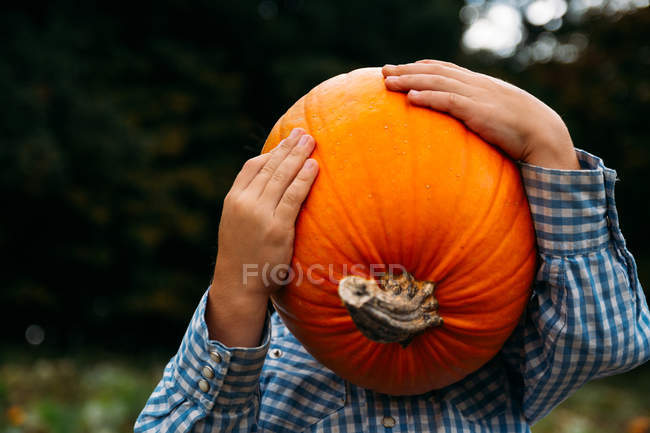 Boy holding a pumpkin in front of his face — Stock Photo
