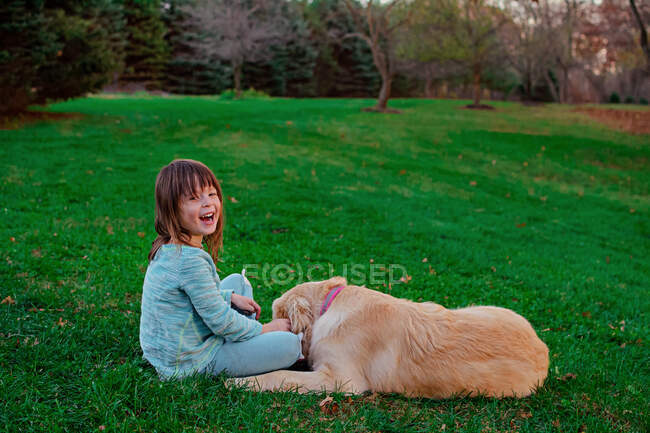 Chica jugando con su perro golden retriever en el jardín - foto de stock
