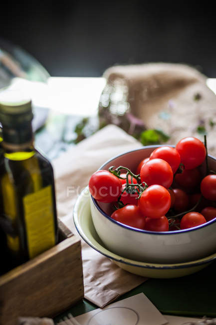 Vista de cerca de los tomates cherry en un tazón junto al aceite de oliva - foto de stock