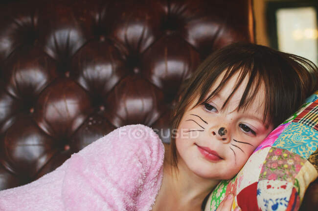 Young girl with Halloween face paint lying on couch — Stock Photo