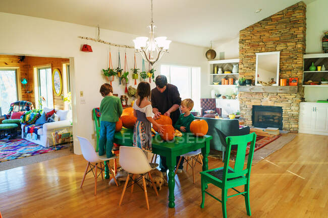 Отец и трое детей готовят тыквы на кухне — стоковое фото