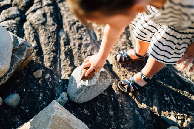 Ragazza raccogliendo pietre in spiaggia — Foto stock