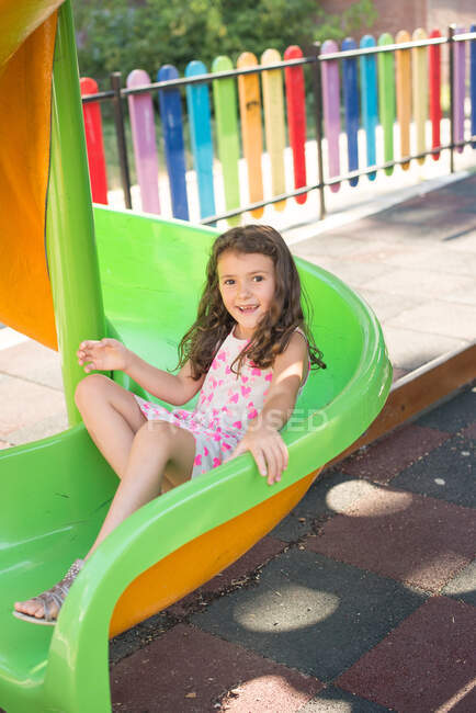 Chica feliz en un tobogán en el patio - foto de stock