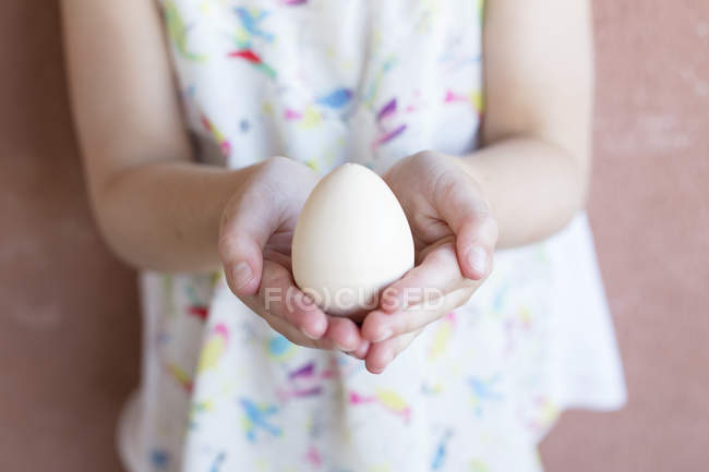 Girl holding an egg in her hands — Stock Photo