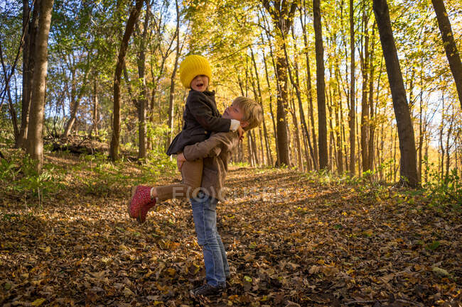 Мальчик поднимает сестру в лесу — стоковое фото