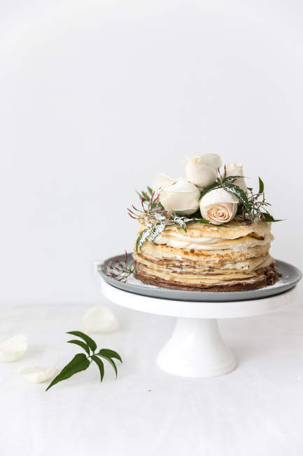 Crepe cake decorated with roses on a cake stand — Stock Photo