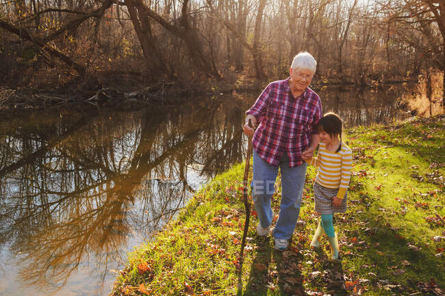 Abuela caminando por el río con su nieta - foto de stock