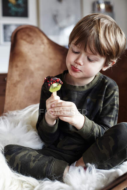 Boy sitting in chair eating healthy treat — Stock Photo