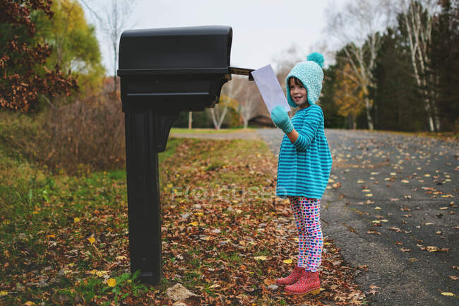 Girl collecting letter from the mail box in the street — Stock Photo