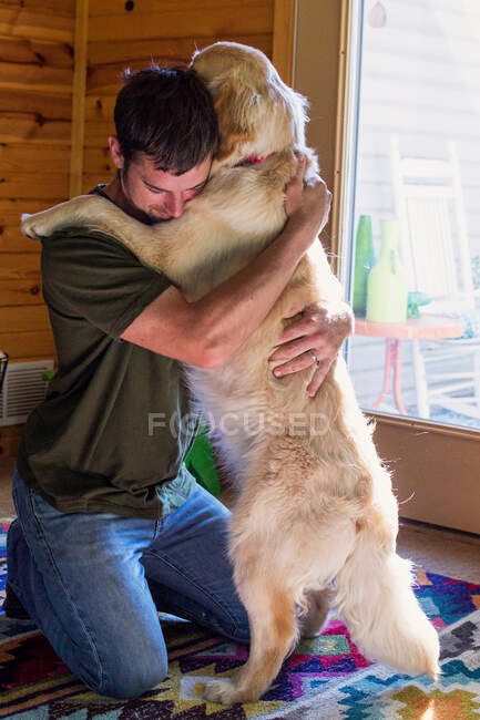 Чоловік обіймає золотошукача собаку — стокове фото