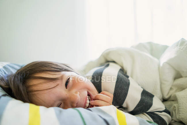 Portrait d'une fille couchée au lit riant — Photo de stock