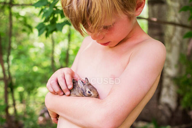 Adorable petit garçon tenant un lapin — Photo de stock