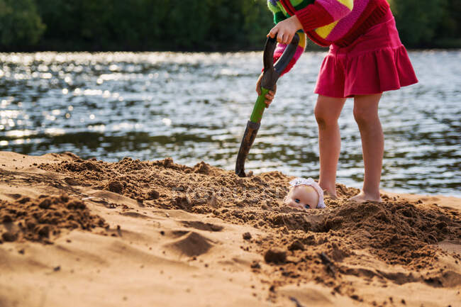 Дівчина ховає ляльку в піску — стокове фото