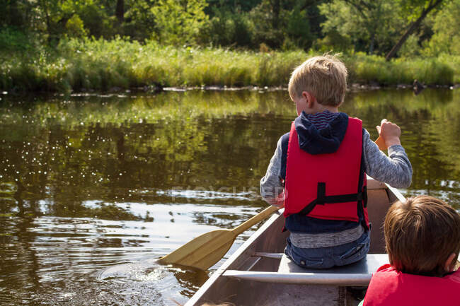 Dois meninos canoagem no lago no dia ensolarado — Fotografia de Stock