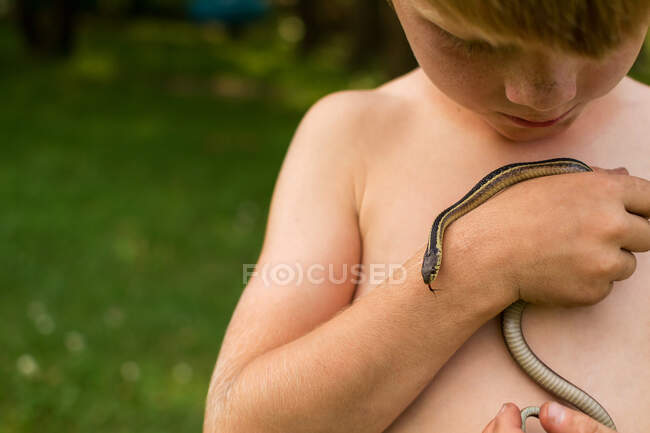 Niño sosteniendo una serpiente en la naturaleza - foto de stock
