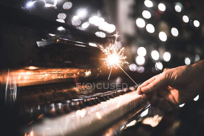 Hand hält Wunderkerze über ein Klavier — Stockfoto