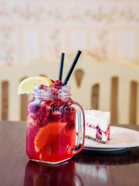 Raspberry lemonade and slice of cheesecake over wooden table — Stock Photo