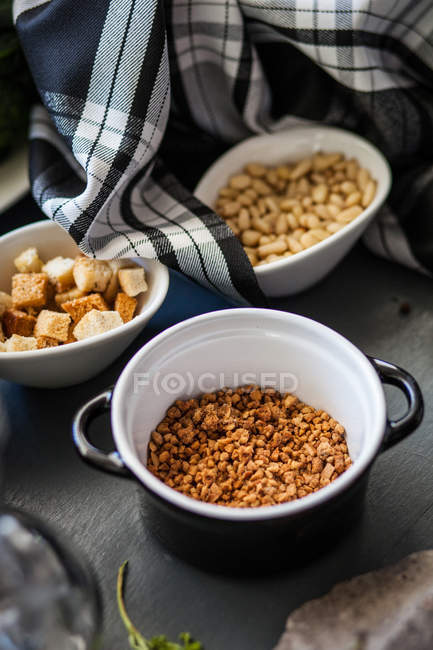 Bowls with nuts and croutons on table with towels — Stock Photo