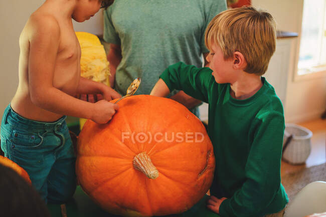 Padre y dos hijos tallando calabazas para Halloween - foto de stock