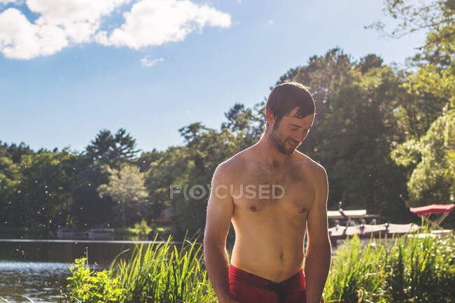 Uomo in piedi vicino a un lago dopo una nuotata — Foto stock