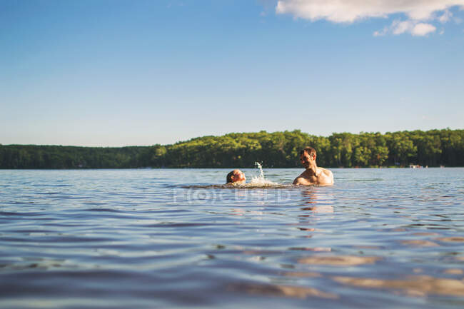Padre insegna a suo figlio a nuotare in un lago — Foto stock