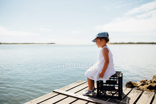 Mädchen sitzt auf einer Kiste auf einem Steg, Noosa Heads, Queensland, Australien — Stockfoto