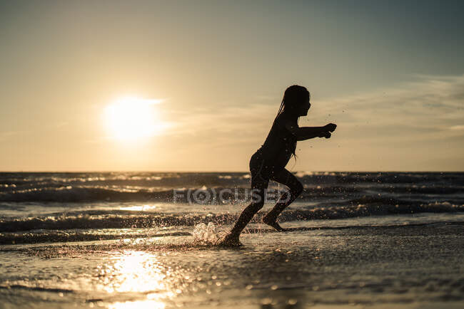 Silhouette Girl läuft am Strand entlang — Stockfoto