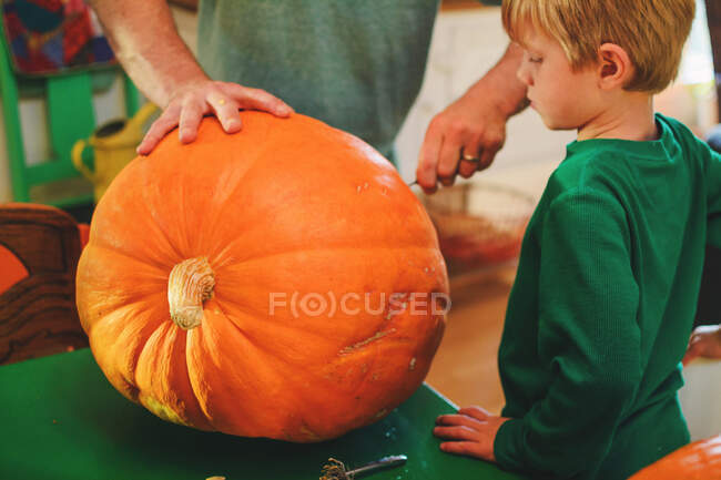 Father helping son carve large pumpkin — Stock Photo