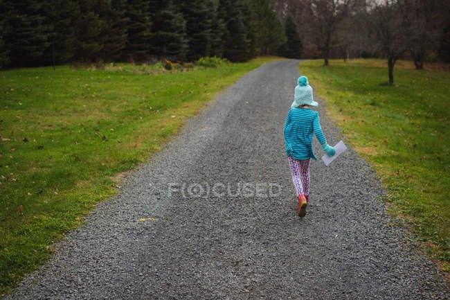Menina segurando uma carta correndo pela calçada — Fotografia de Stock