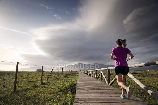 Vue arrière du jogging féminin le long de la promenade, Tarifa, Cadix, Andaulcia, Espagne — Photo de stock