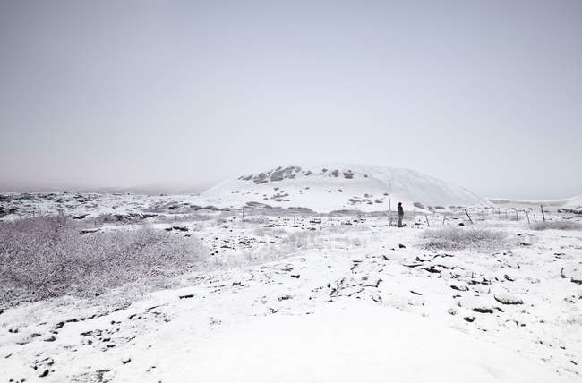 Vista distante do homem em pé na paisagem de inverno nevado, Islândia — Fotografia de Stock