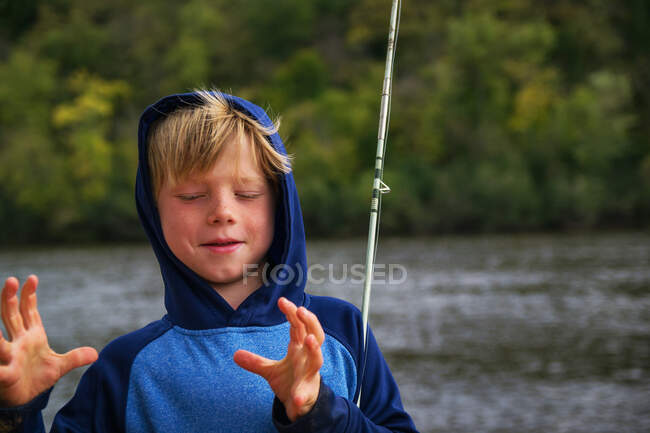 Niño pescando mostrando el tamaño de la captura - foto de stock
