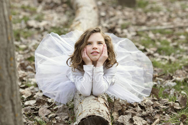 Дівчина в сукні, що лежить на стовбурі дерева — стокове фото