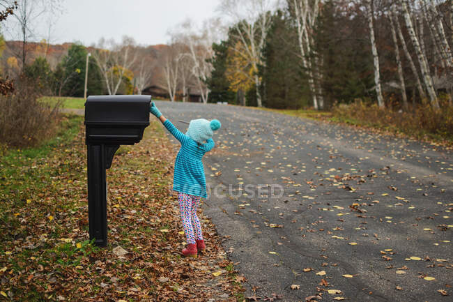 Girl collecting letter from the mail box in the street — Stock Photo