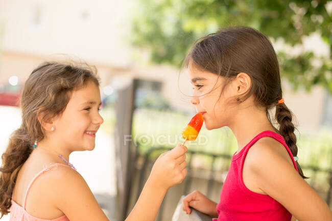 Due ragazze che condividono un ghiacciolo — Foto stock