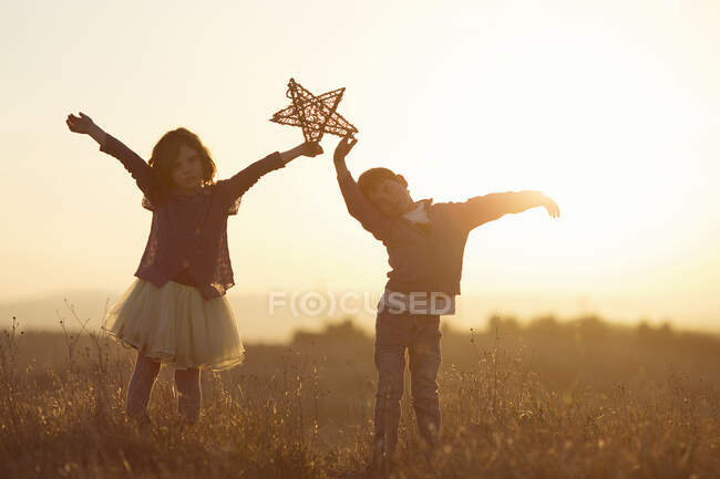 Duas crianças segurando uma estrela no ar — Fotografia de Stock