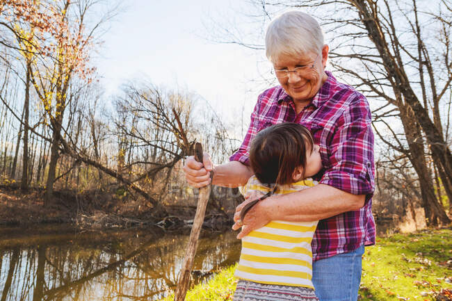 Mädchen umarmt ihre Großmutter im Wald an einem Fluss — Stockfoto