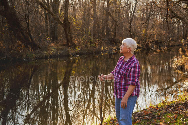Senior woman standing by a river — Stock Photo