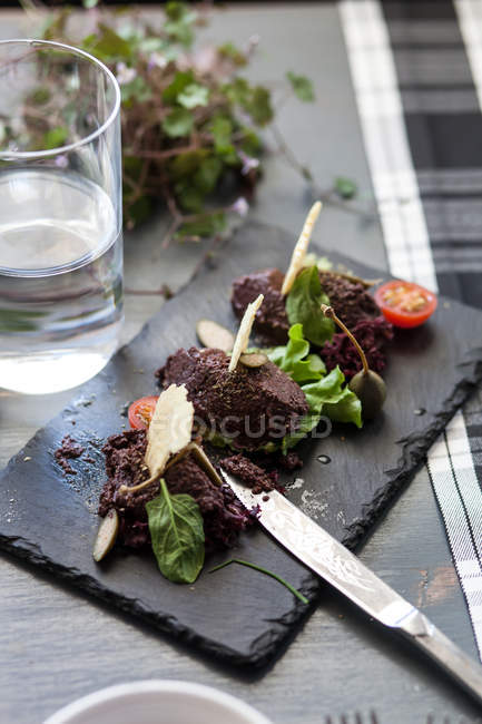 Olive tapenade starter with glass of water — Stock Photo