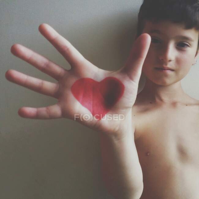 Niño con el corazón dibujado en su mano - foto de stock